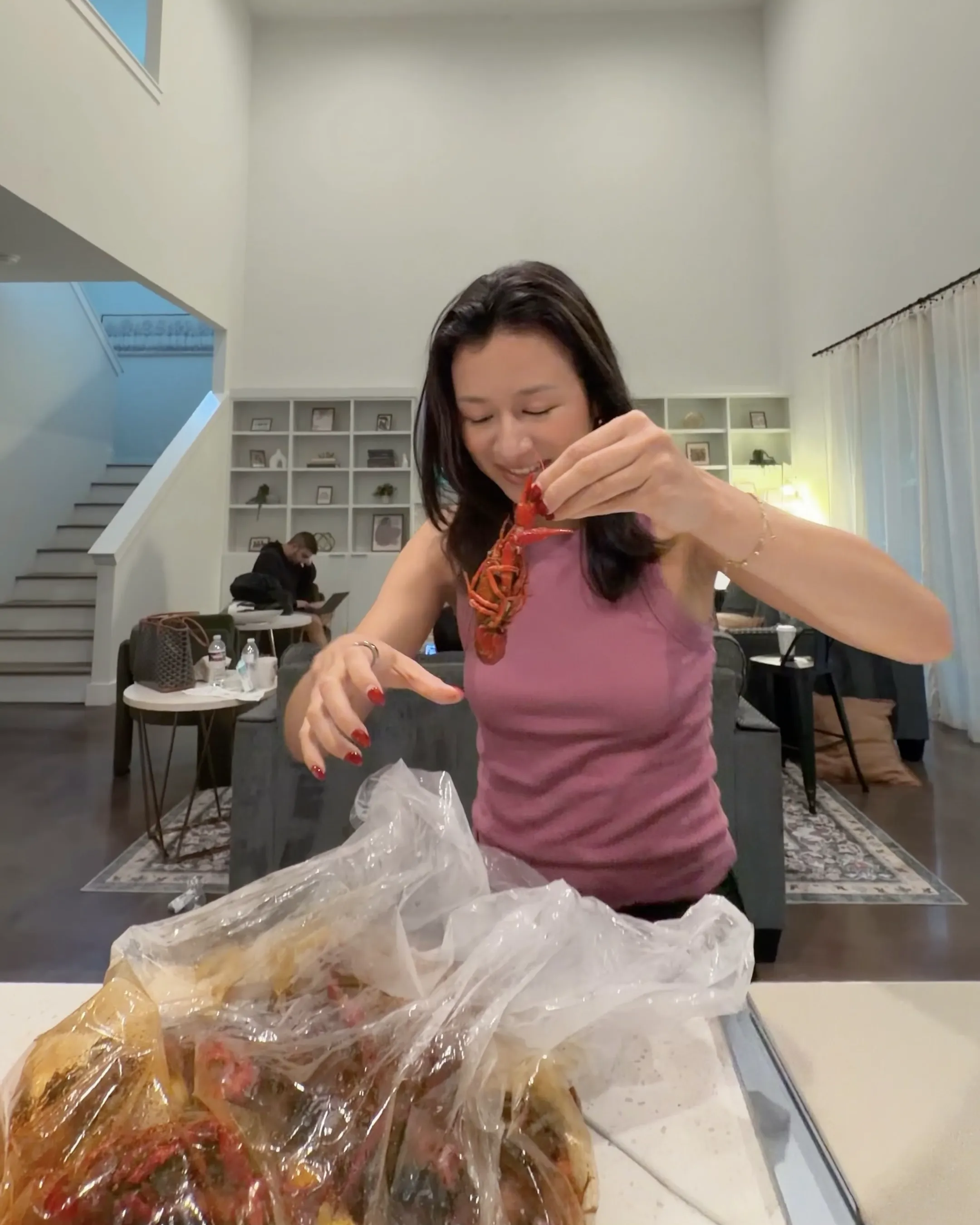 Eileen holding up a crawfish over a bag of seafood boil