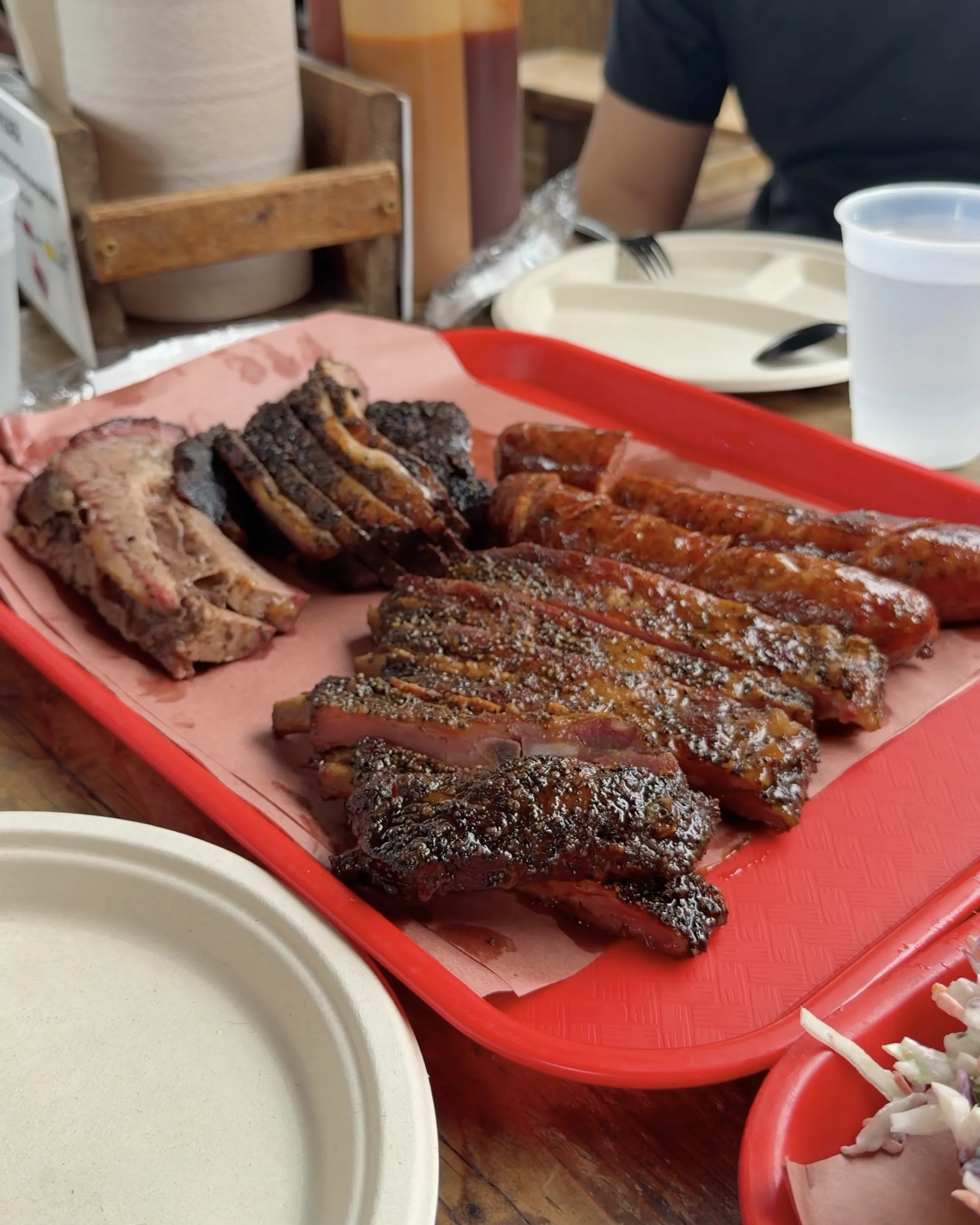 A tray of smoked brisket, ribs and sausage on butcher paper