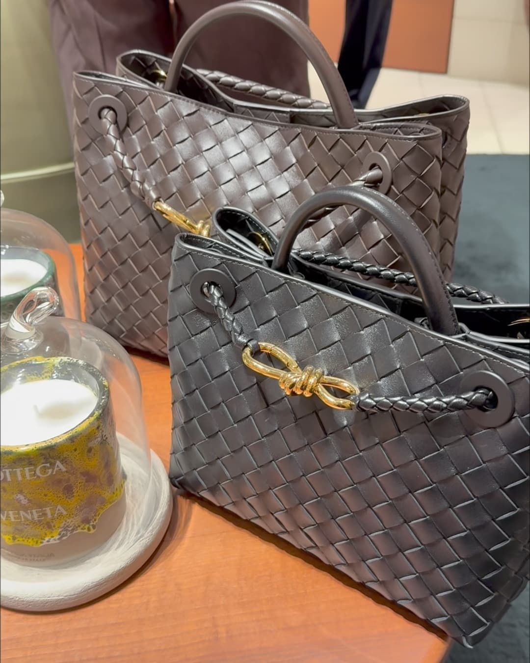 The Bottega Veneta Andiamo in brown woven leather with a gold knot closure, on a table in the boutique