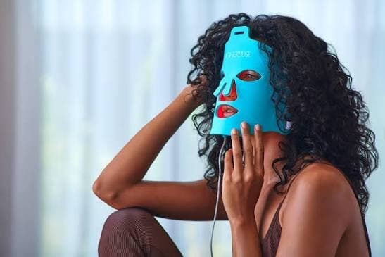 A woman wearing the teal HigherDose Red Light Face Mask