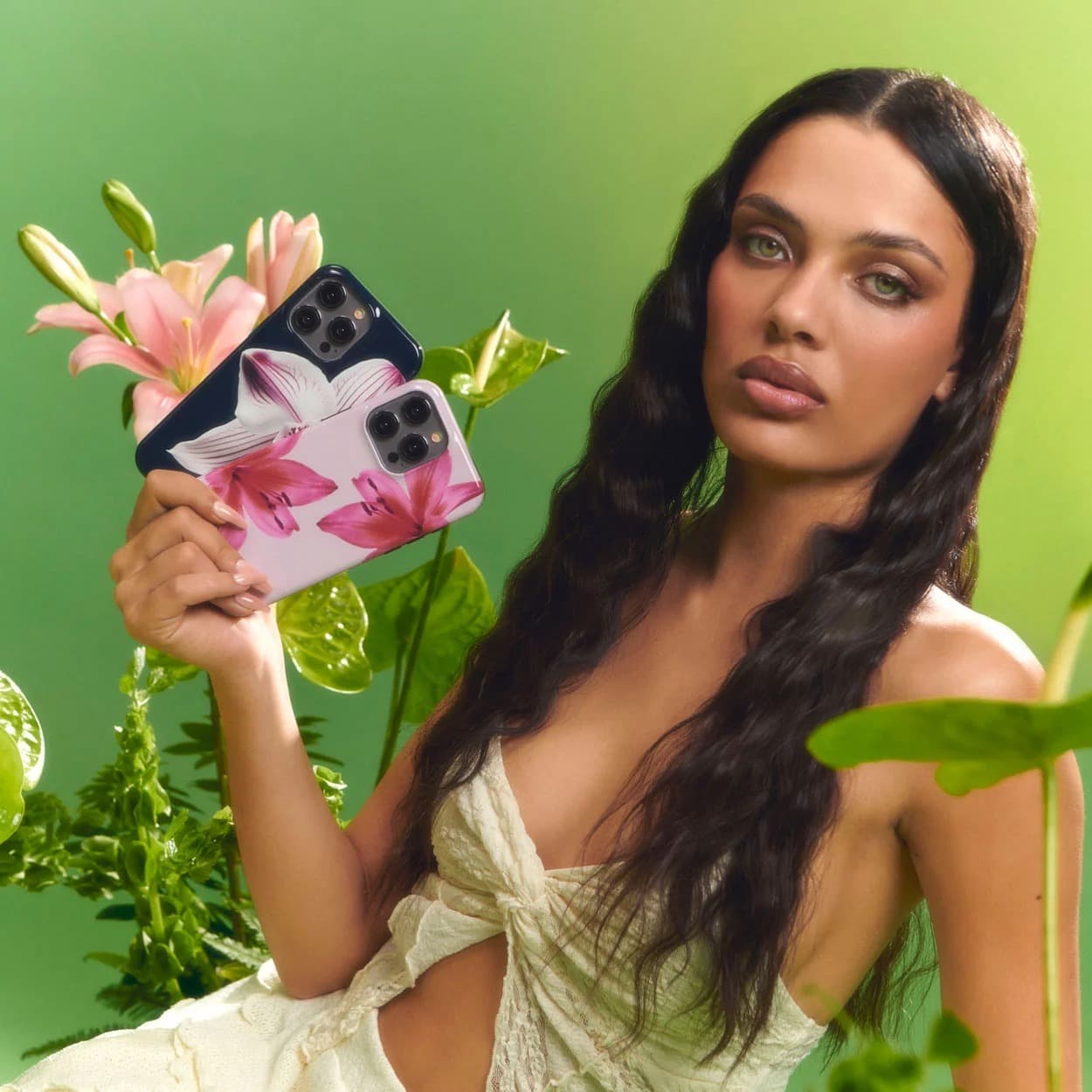A model holding two Burga floral cases, navy and pink lily, against a green backdrop