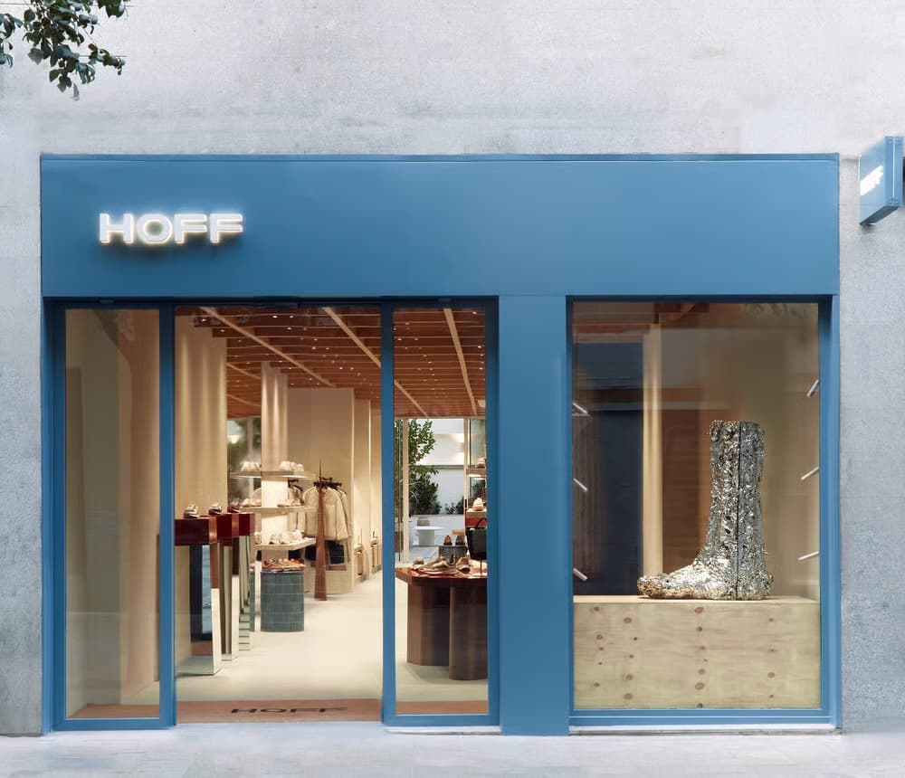 The blue HOFF storefront in Spain, its lit-up sign above a window of shoes