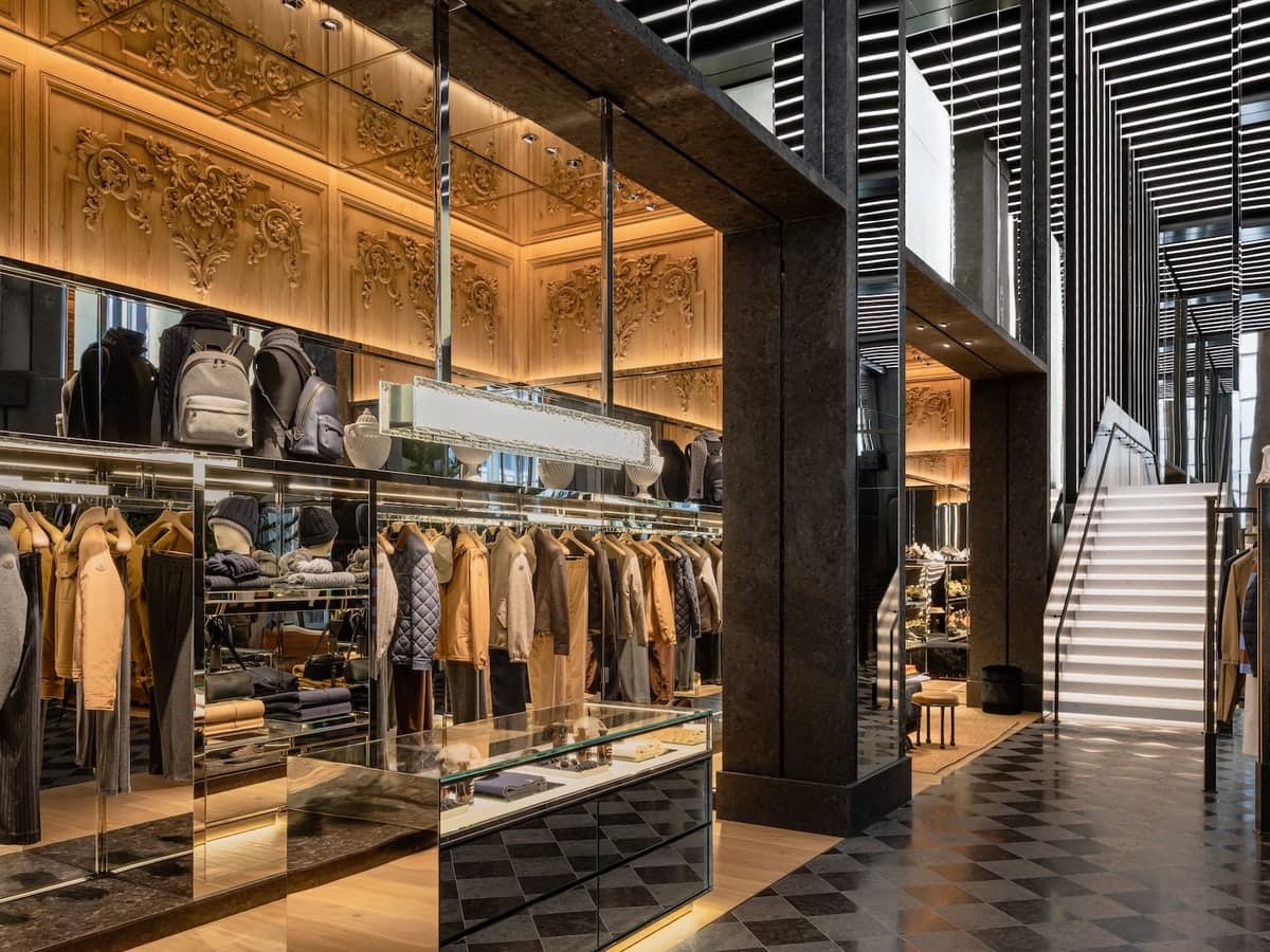 The Moncler boutique, with jackets on racks under carved gold panels and a staircase