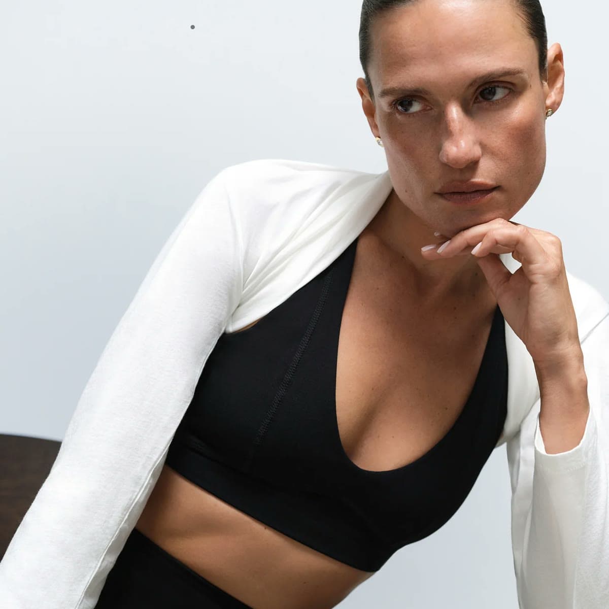 A woman in a black Mate the Label organic cotton bra under a white shrug