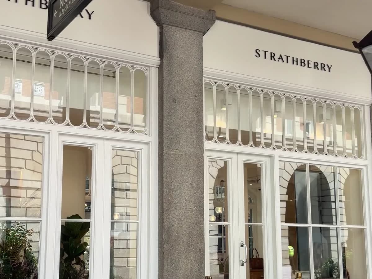 The Strathberry shop on Duke of York Square: a white-framed Georgian shopfront under a colonnade, with the hanging Duke of York Square sign above it